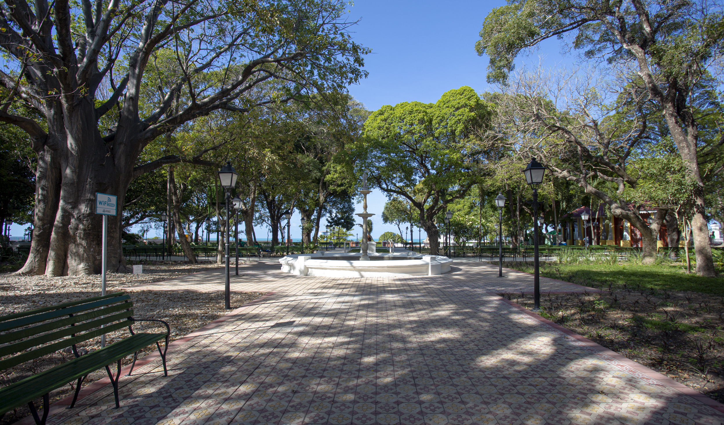 passeio publico com fonte ao fundo, banco e vista para o mar